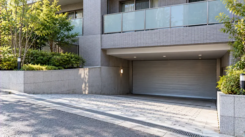 分譲マンションの半地下駐車場の入口に、シャッターが下りている様子を歩道から斜めにのイメージ
