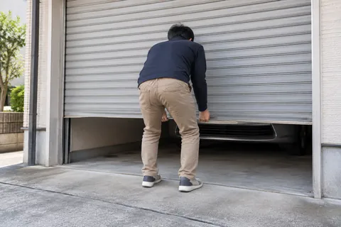 重くなった手動のガレージシャッターを持ち上げる様子（イメージ）