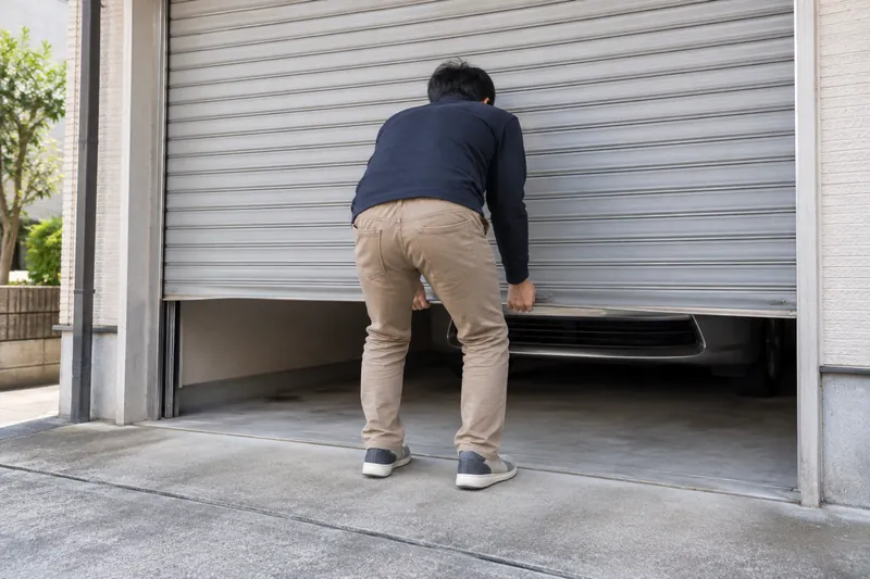 重くなった手動のガレージシャッターを持ち上げる様子（イメージ）