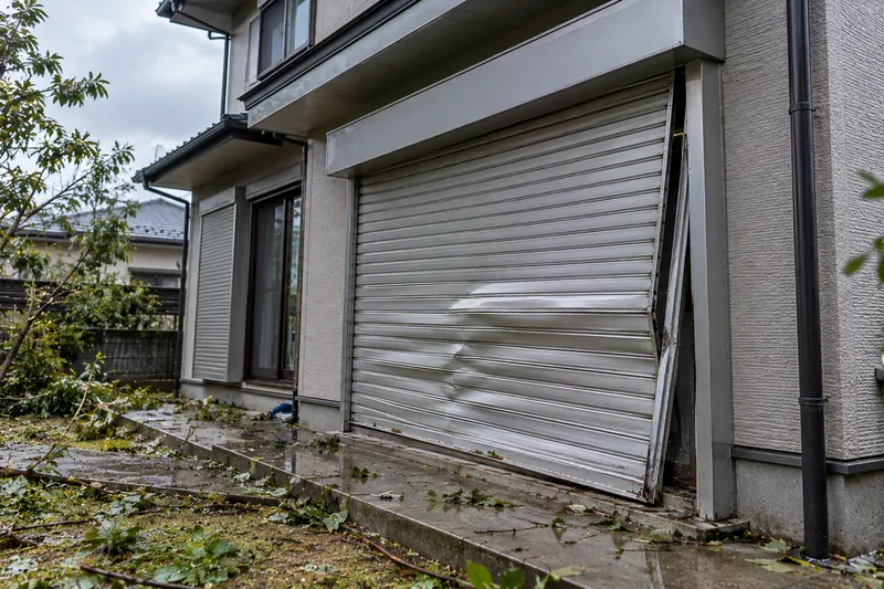 台風のあとにへこんでレールから外れた住宅の窓シャッター(イメージ)