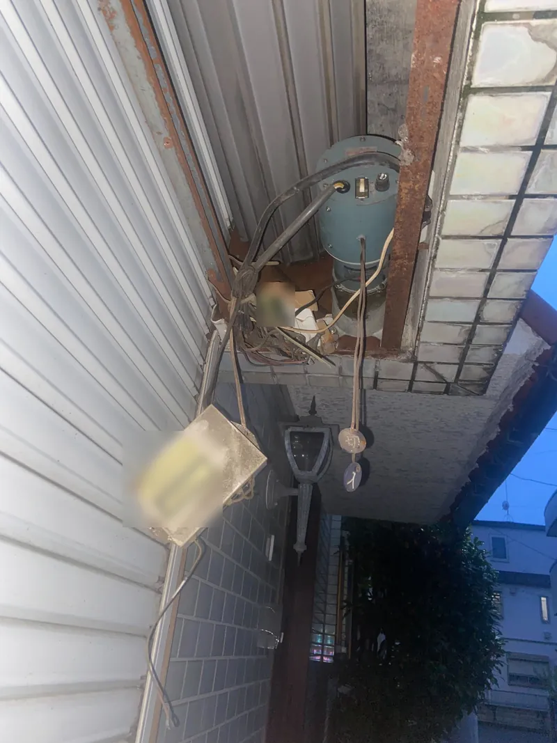 荒川区の住宅ガレージで、交換前の電動シャッターの開閉機と巻き取り部を見上げた写真