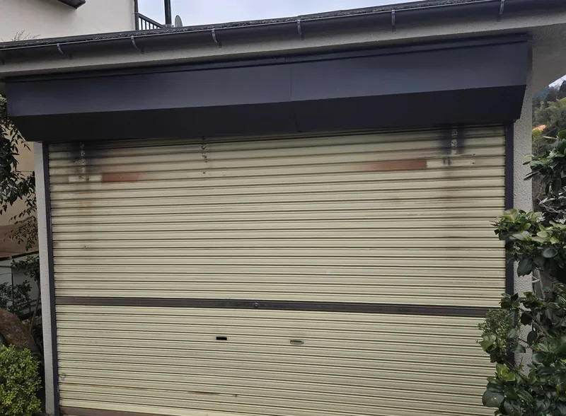 青梅市の住宅ガレージで、工事前の軽量手動シャッター（上部にさびや汚れが出ている状態）